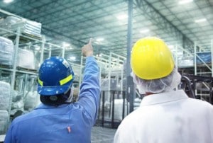 Two men wearing helmets in a warehouse 